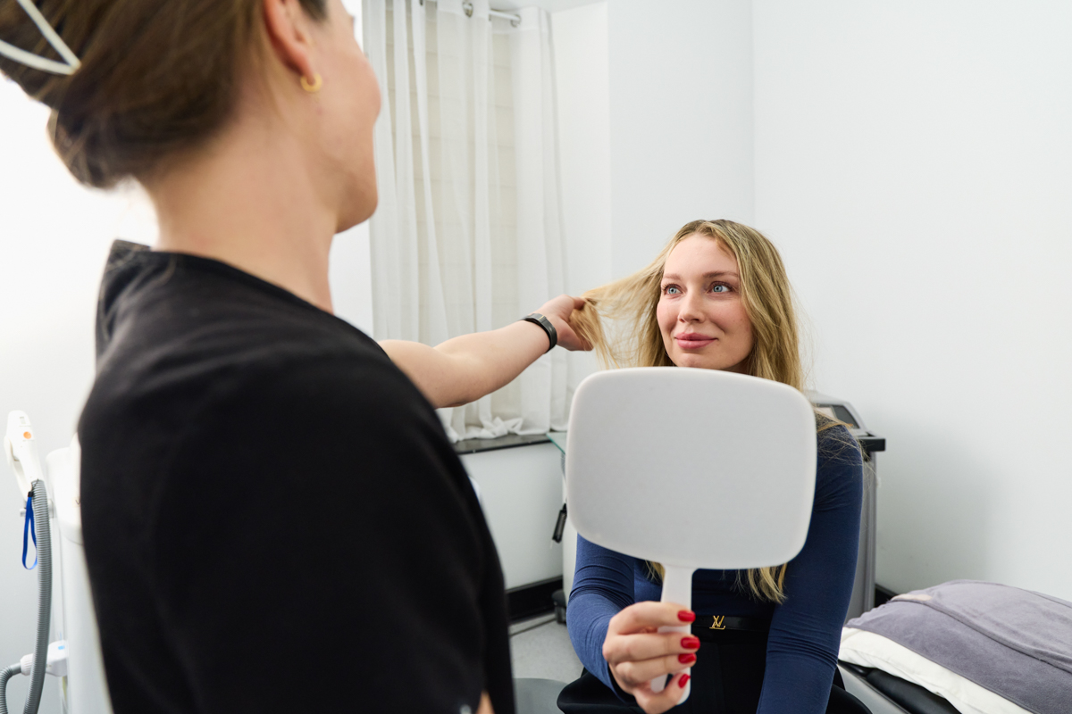 Patient reviewing results in a hand mirror at The Aesthetic Laser Centre