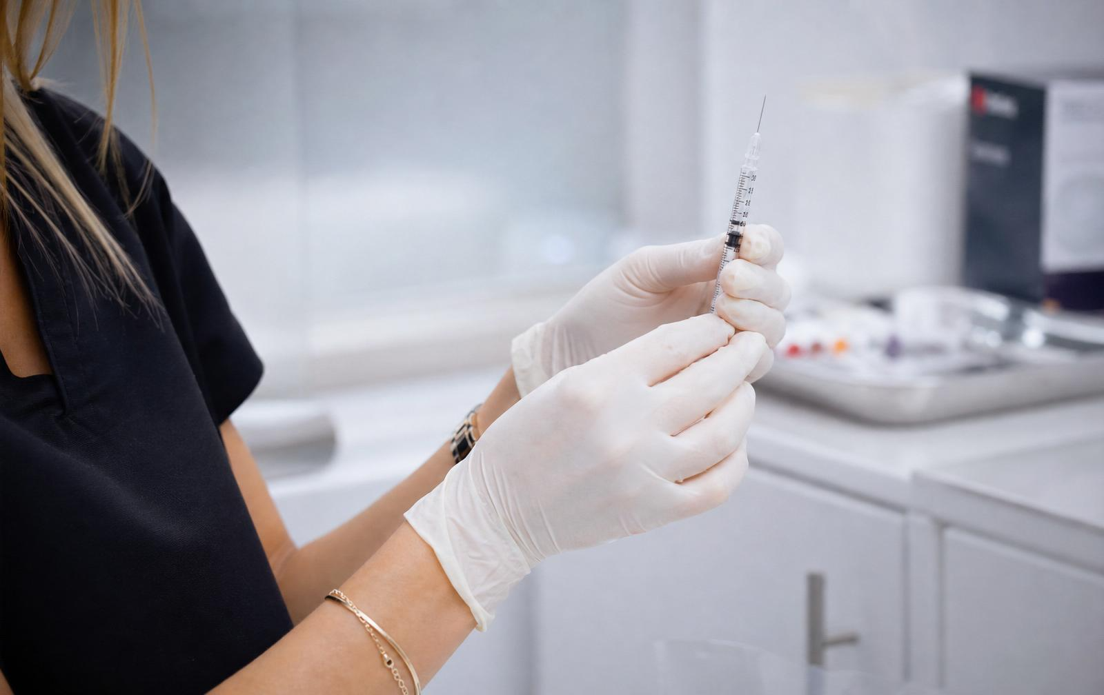 Gloved cosmetic nurse preparing a fine syringe for a Botox treatment in a clean Hobart clinic