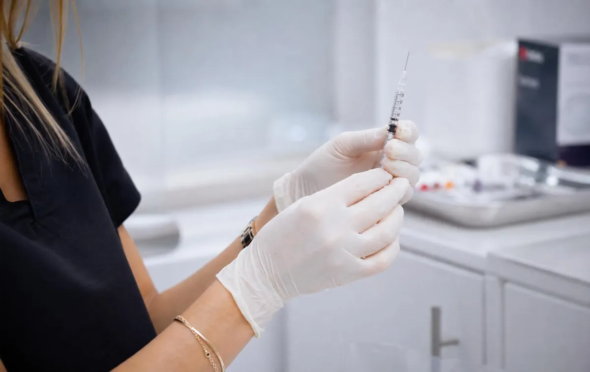 Gloved cosmetic nurse preparing a fine syringe for a Botox treatment in a clean Hobart clinic