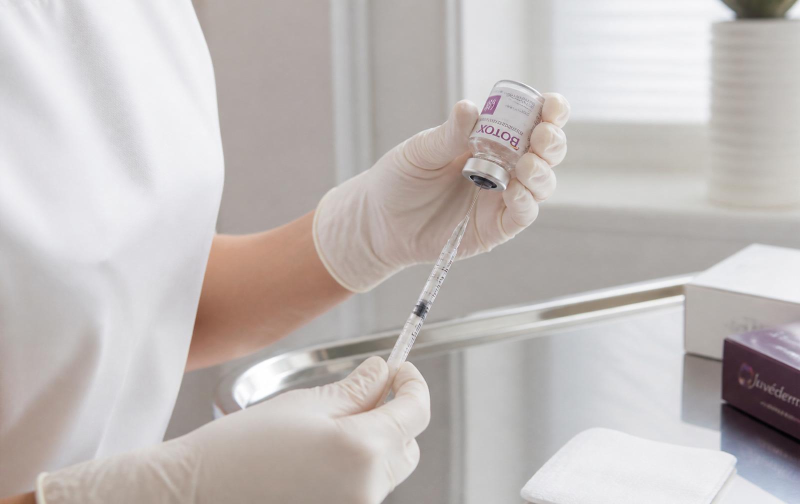 Gloved clinician drawing a small dose of Botox from a labelled vial into a fine syringe