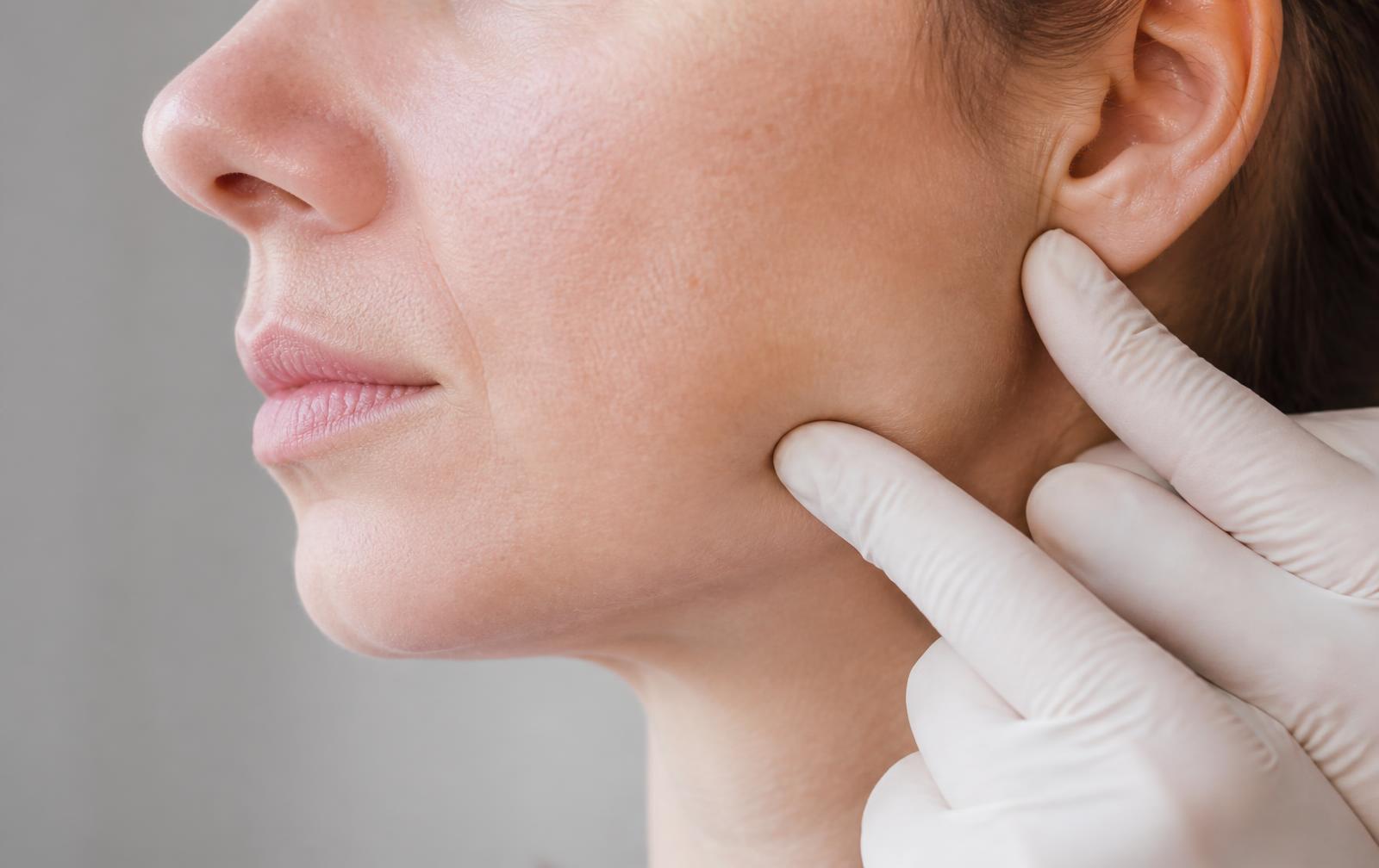Practitioner assessing the masseter muscle along a patient's jawline