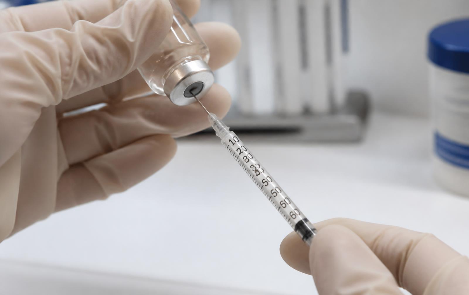 Gloved clinician drawing a precise dose of botulinum toxin from a vial into a fine syringe