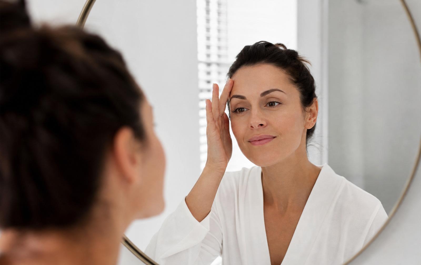 Woman checking her smooth forehead in a minimalist mirror